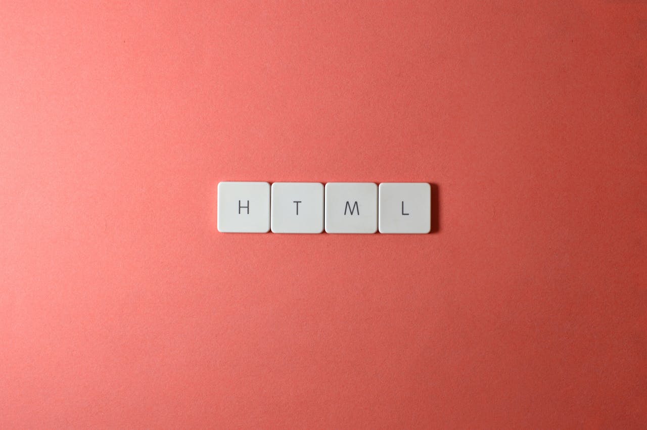 services-04 Minimalist design of HTML letter tiles on a salmon pink surface.